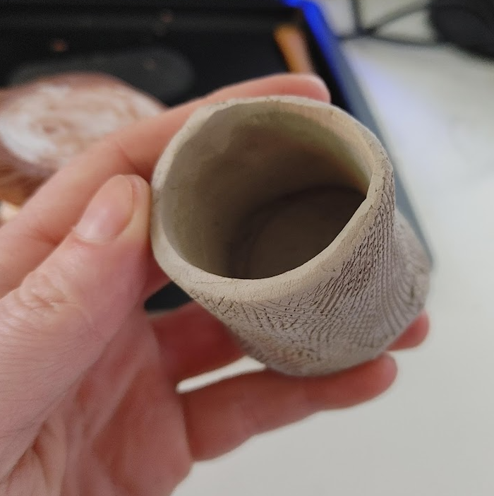 Hand made clay form with rough surface held in left hand